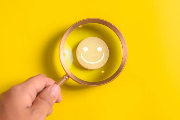 istock satisfaction with smiley face emoticon on wooden yellow background. 1494928153