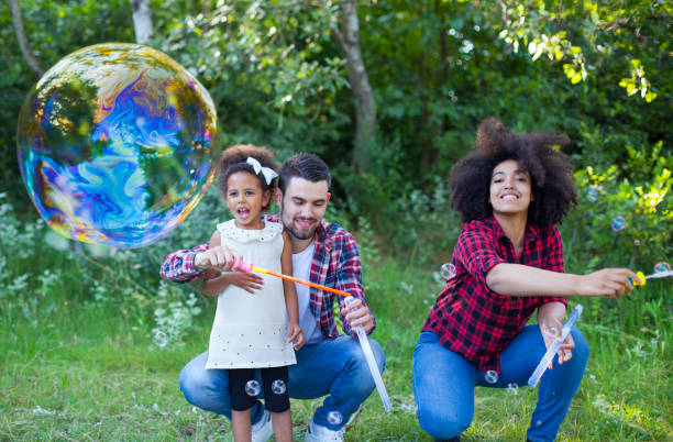 istock Happy family playing soap bubbles in park 1494931575
