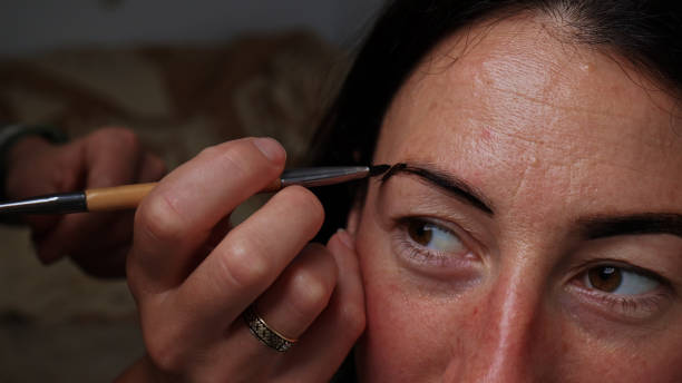 istock Applying makeup to a girl's face close-up, brush and hands master. 1494933419
