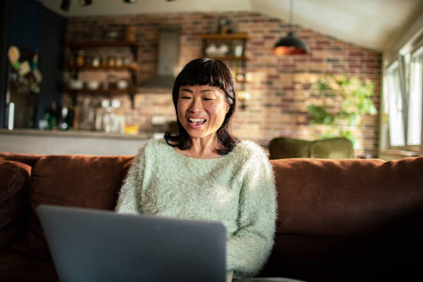 istock Young Japanese Woman using a laptop on a couch 1494936822