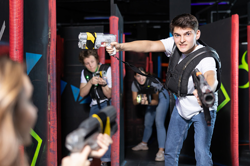 Excited teenager having fun playing lasertag in arena
