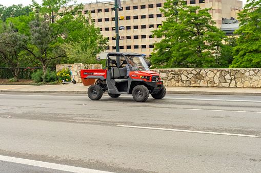 San Antonio, Texas, USA – May 9, 2023: A red Gravely Atlas 3400 side-by-side utility truck traveling on a downtown street in San Antonio, Texas.