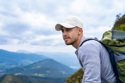 Portrait of a young Latino outdoorsman sitting on top of a mountain, hiking in the mountains of Colombia, lifestyle, travel and adventure concept.