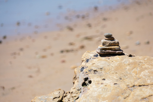A stack of sand-covered rocks with a sandy, blurred background and space for text