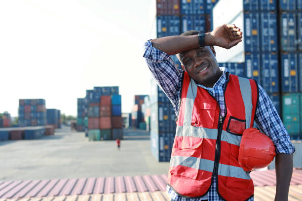 istock Foreman engineer man standing and holding hard hat while wipe the sweat away. Confident engineering work at container cargo site and checking industrial container cargo freight ship 1494967182