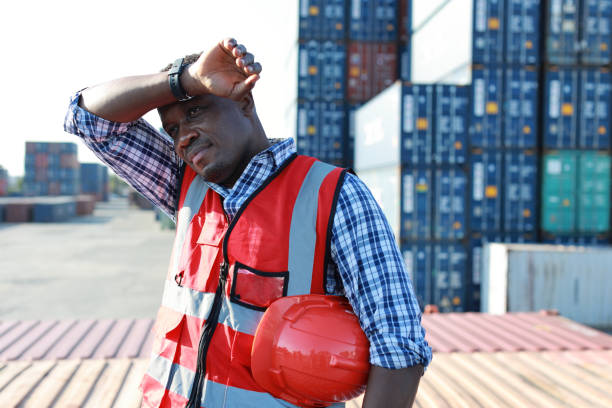 istock Foreman engineer man standing and holding hard hat while wipe the sweat away. Confident engineering work at container cargo site and checking industrial container cargo freight ship 1494967193