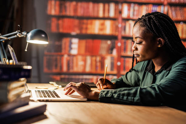 istock Young woman using laptop, writing notes and studying at the library 1494967464