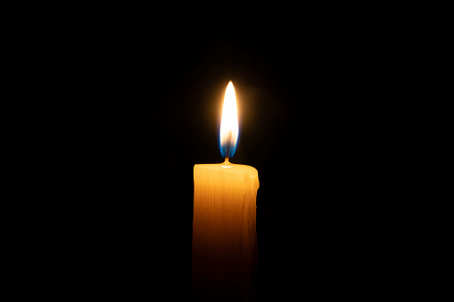 a orange candle burns on a black background with a reflection copy space,