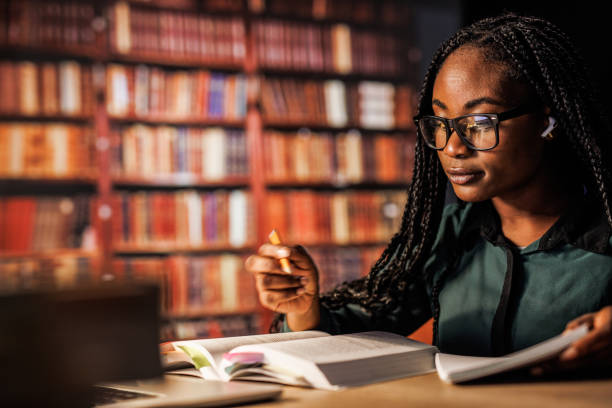 istock Young woman reading a book and writing notes when studying for exam 1494969201