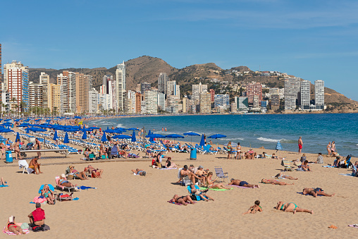 benidorm spain  april - 14 - 2023 \n - Many unknown tourists lie on the sandy Levante beach in the city of Benidorm in the Alicante region of Spain