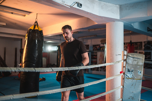 Photo of a young and handsome boxer with muscular build body with red gloves training in a gym