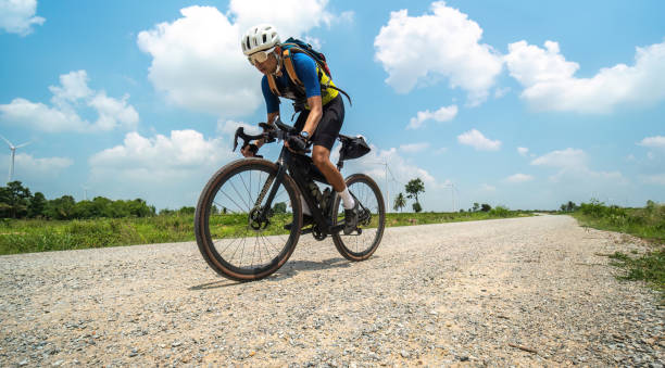 Asian man riding bicycle on gravel road at high speed stock photo