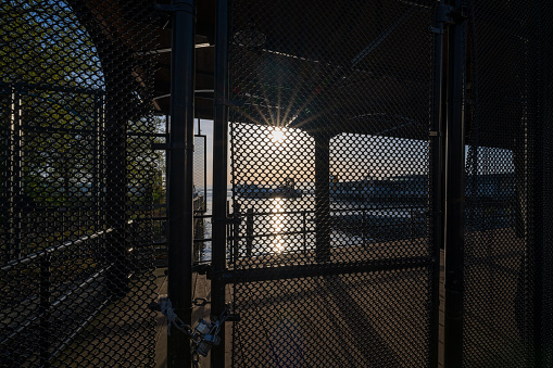 A sunset viewed through a chain link fence on the Seattle waterfront.