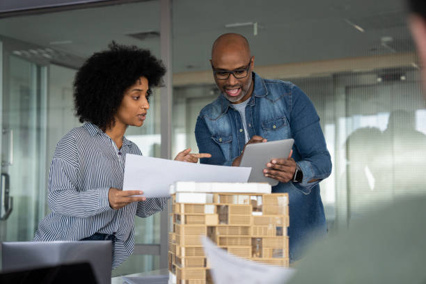 istock Two African-American architects checking design on blue print 1494994654