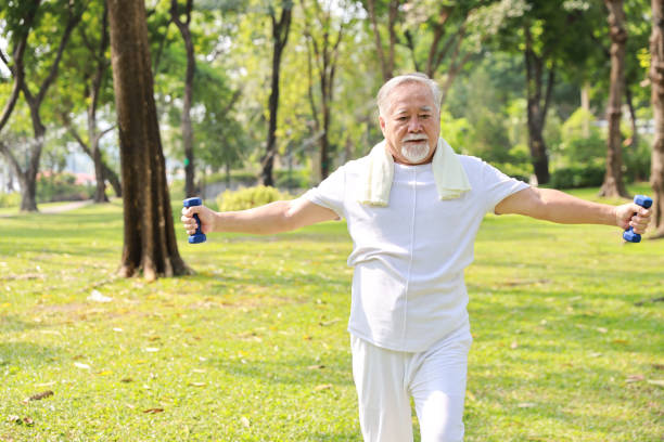 istock Happy and smiling asian senior man doing arm work out and lifting dumbbell exercise with relaxation for healthy in park outdoor after retirement. Health care elderly outdoor lifestyle concept. 1494994913