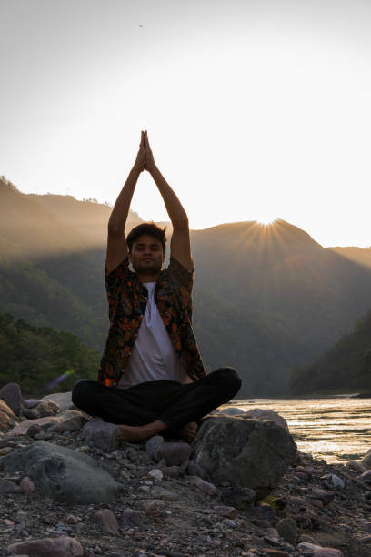 istock Young man meditating on rocks at lakeshore during vacation 1494995659