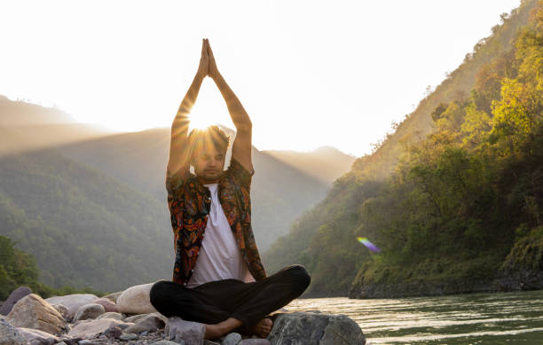 istock Young man meditating on rocks at lakeshore during vacation 1494995679