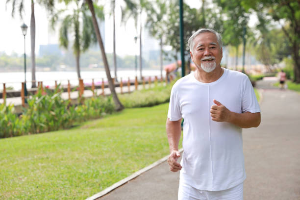 istock Happy and smiling asian senior man doing exercise and jogging or walking with relaxation for healthy in park outdoor after retirement during summer time. Health care elderly outdoor lifestyle concept. 1494995792
