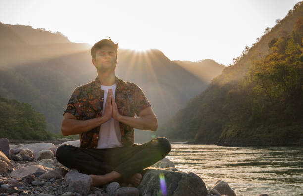 istock Young man meditating on rocks at lakeshore during vacation 1494999357