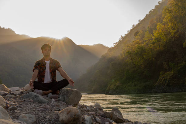 istock Young man meditating on rocks at lakeshore during vacation 1494999366