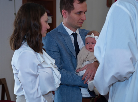 Priest is babtizing little baby with holy water