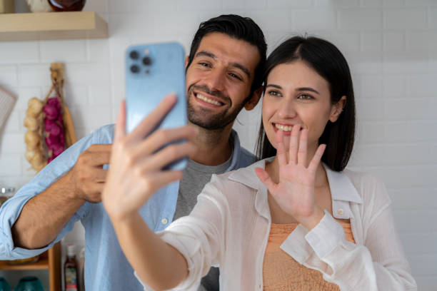 istock Housekeepers taking selfie while resting, using mobile phone, young couple hugging and smiling at camera, standing on floor among cleaning tools and supplies, kitchen interior. 1495000808