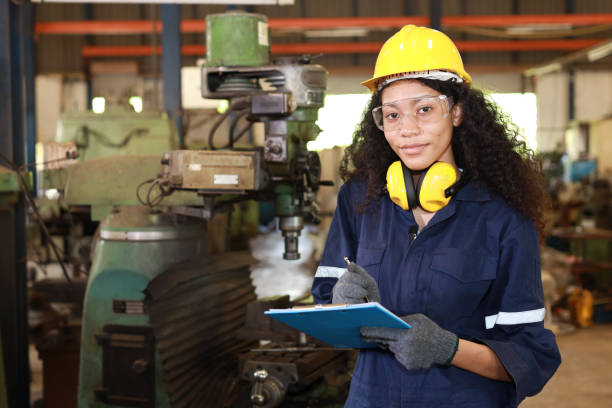 istock Technician engineer or worker woman in protective uniform and safety hat maintenance operation or check lathe metal machine with clipboard at heavy industry manufacturing factory. Metalworking concept 1495000992