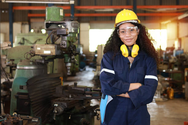 istock Technician engineer or worker woman in protective uniform with safety hardhat maintenance operation or checking lathe metal machine at heavy industry manufacturing factory. Metalworking concept 1495001007