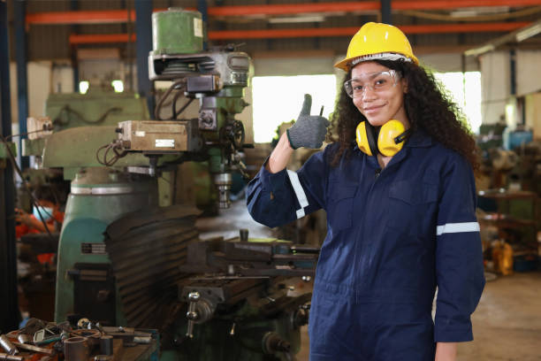 istock Technician engineer or worker woman in protective suit smiling and showing thumb up maintenance operation or checking lathe metal machine at heavy industry manufacturing factory. Metalworking concept 1495001019