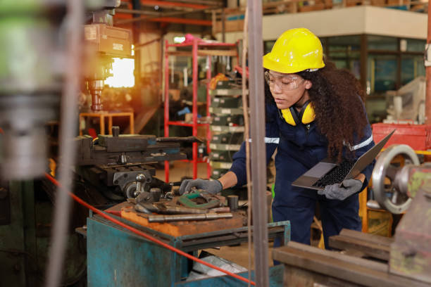 Technician engineer or worker woman in protective uniform and safety hat maintenance operation or check lathe metal machine with computer at heavy industry manufacturing factory. Metalworking concept ingeniero técnico o mujer trabajadora con uniforme de protección y operación de mantenimiento de sombrero de seguridad o máquina de control de torno metálico con computadora en fábrica de fabricación de industria pesada. concepto metalúrgico