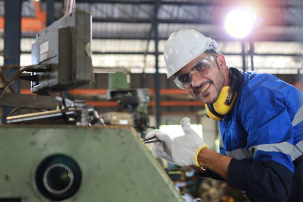 istock Technician engineer or worker man in protective uniform with safety hardhat maintenance operation or checking lathe metal machine at heavy industry manufacturing factory. Metalworking concept 1495001138