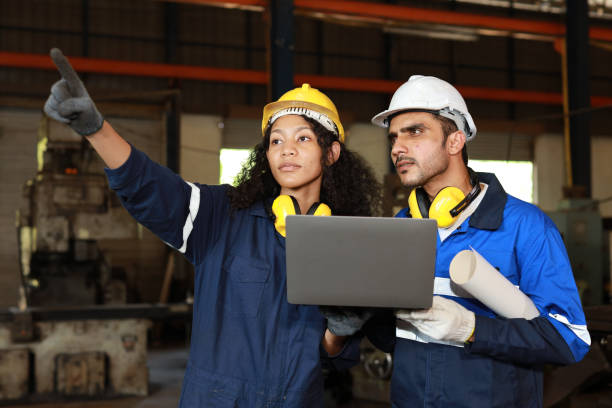istock Group of technician engineer in protective suit using walkie talkie radio and computer while pointing and controll maintenance operation work lathe metal machine at industry manufacturing factory 1495001306