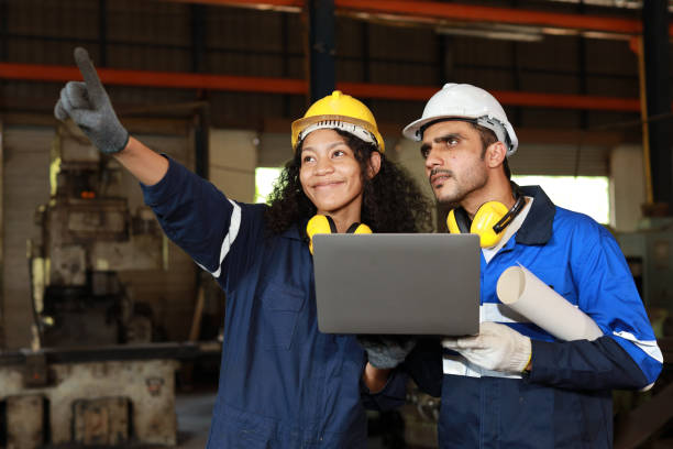 istock Group of technician engineer in protective suit using walkie talkie radio and computer while pointing and controll maintenance operation work lathe metal machine at industry manufacturing factory 1495001311