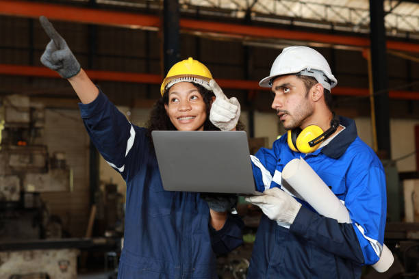 istock Group of technician engineer in protective suit using walkie talkie radio and computer while pointing and controll maintenance operation work lathe metal machine at industry manufacturing factory 1495001312