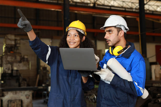 istock Group of technician engineer in protective suit using walkie talkie radio and computer while pointing and controll maintenance operation work lathe metal machine at industry manufacturing factory 1495001314