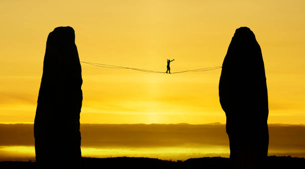Silhouette of tightrope walker balancing on the rope Man balancing on the rope challenge and risk taking concept of risk taking highlining stock pictures, royalty-free photos & images