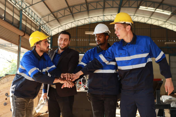 istock Group of technician engineer and businessman in protective uniform with hardhat standing and stacking hands celebrate successful together or completed deal commitment at metal lathe factory industry 1495002501