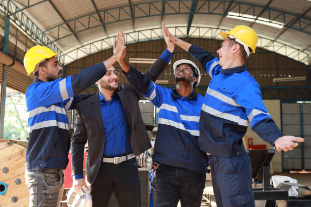 istock Group of technician engineer and businessman in protective uniform with hardhat standing and raising hands celebrate successful together or completed deal commitment at metal lathe factory industry 1495002506