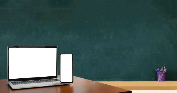 istock Laptop, smartphone, blank screen lies on wooden table for foreground. Blackboard is Empty, Education is important for everyone, because it helps to succeed. To stimulate teaching. 1495002761