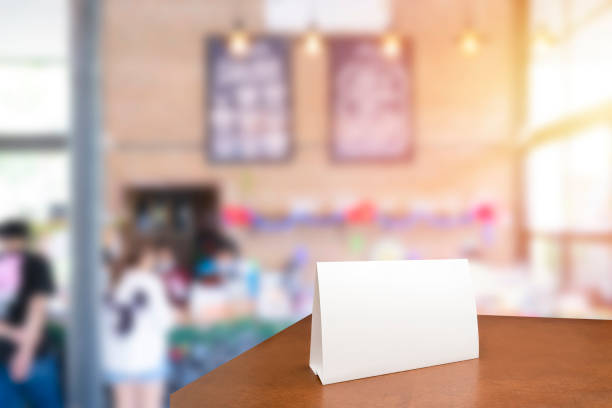 istock Menu frame mockup standing on wooden table in cafe restaurant bar. Space for text. Blank menu frame label mockup in restaurant bar stand. 1495003842