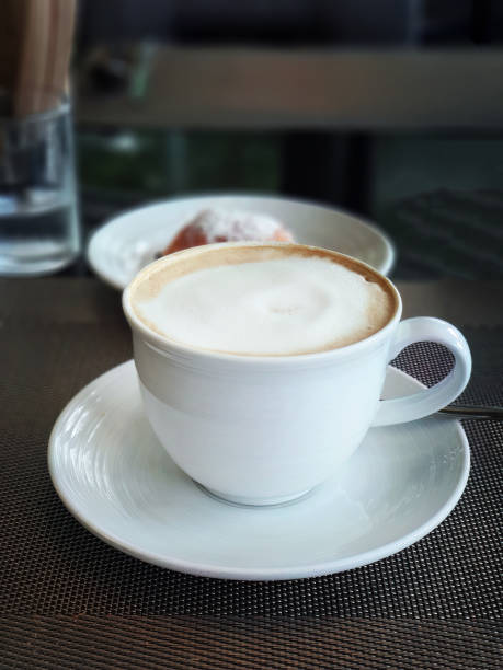 istock High angle view a cup of latte, mocha or cappuccino coffee in the white cup on breakfast table with dark background 1495005462