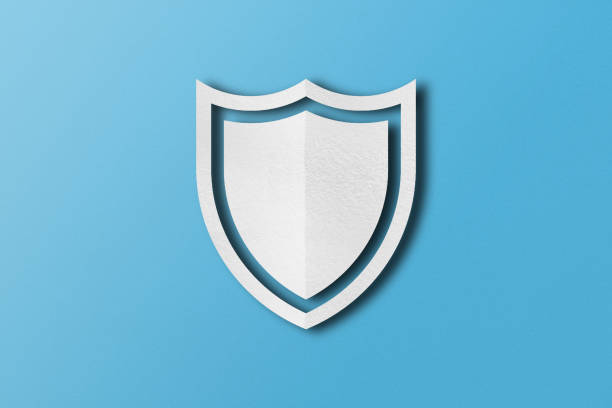 istock white paper shield Punched paper cut out shield shape set on light blue paper background. 1495006713