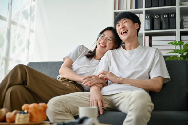 かわいいアジアの若いガールフレンドが彼氏と笑いながら一緒にテレビを見ています。 - apartment television family couple ストックフォトと画像