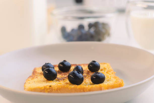 French toast with Blueberries on white plate for breakfast. Fried bread slices with milk.