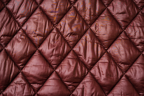 Quilted fabric background texture blanket or puffer jacket.padded, down jacket. Background of urban winter outfit.Quilted pattern.Banner.