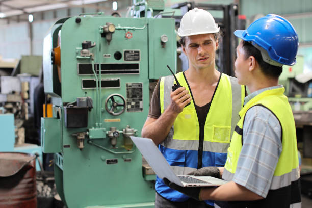 istock Technician engineer or worker man in protective suit standing and using walkie talkie radio while controlling or maintenance operation work lathe metal machine at heavy industry manufacturing factory 1495013376