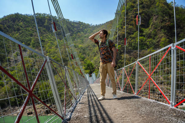 istock Cheerful male explorer standing on footbridge against lush mountain 1495014166