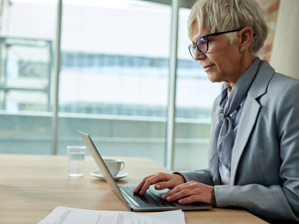 istock Mature female entrepreneur typing an e-mail on a computer in a modern office. 1495020042