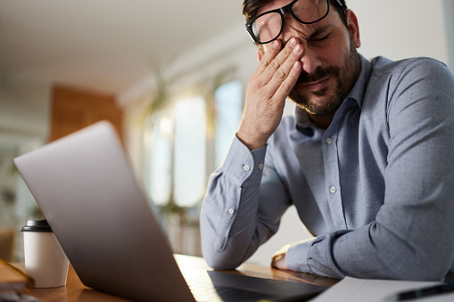 Male entrepreneur having a headache after working on a computer at home office.