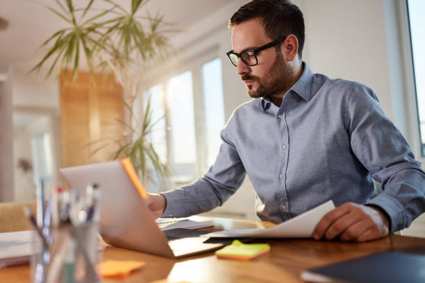 istock Male entrepreneur working on laptop and reports at home office. 1495021307